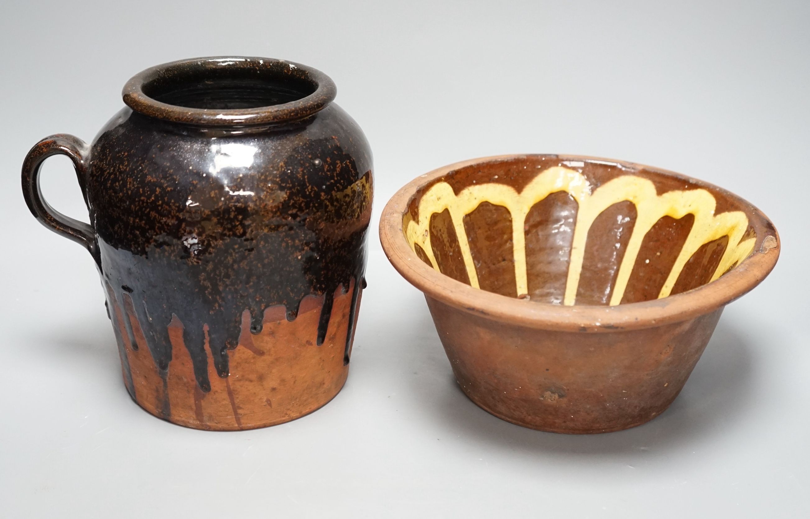 A 19th century slipware bowl and brown glazed single handled storage jar, 21cm tall, (2)